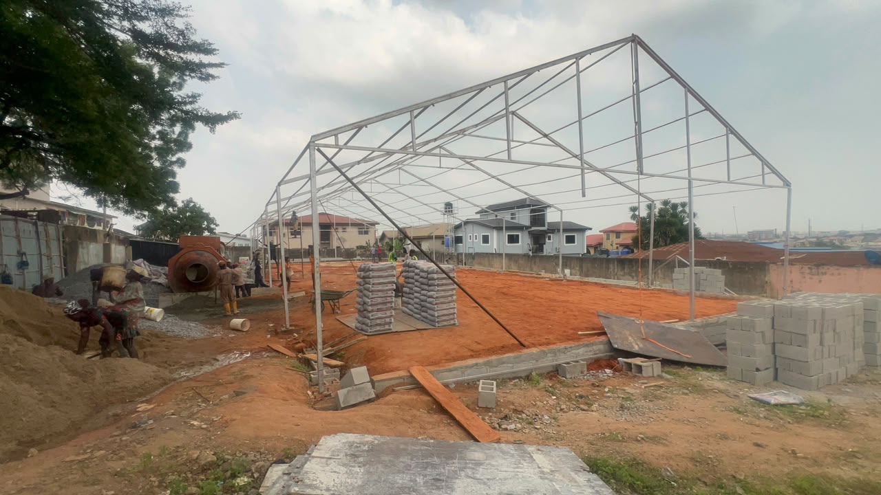 Open steel frame structure being erected on a red-dirt construction site